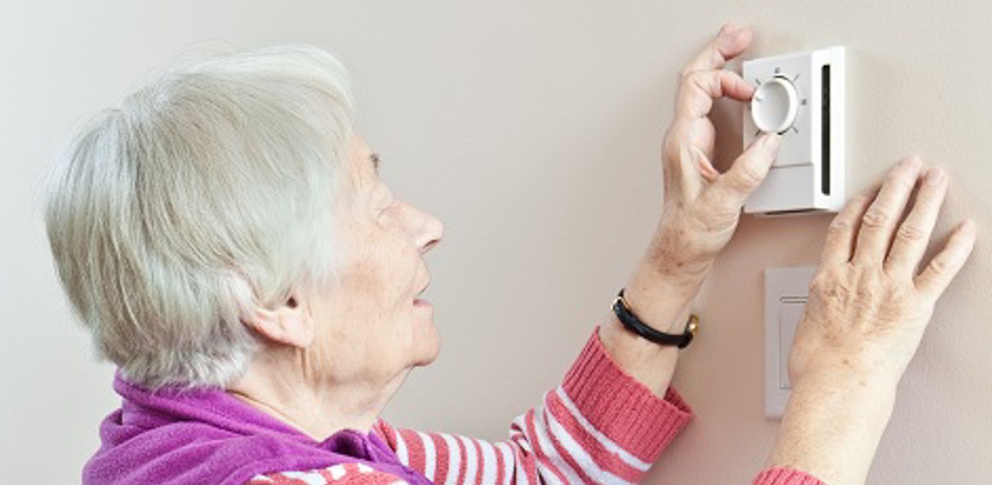 nojs Lady looking at heating thermostat on wall