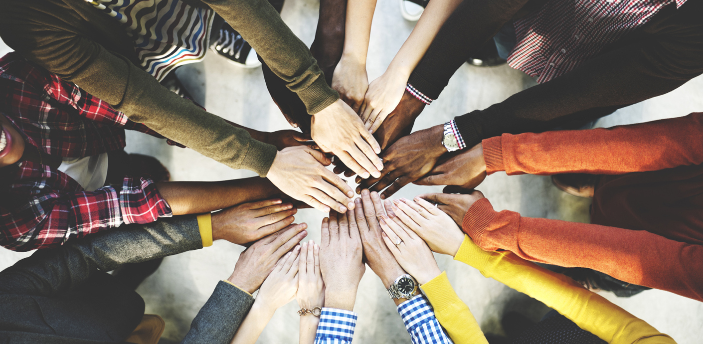 nojs From above - A group of people in a circle facing each other holding out their arms and hands.