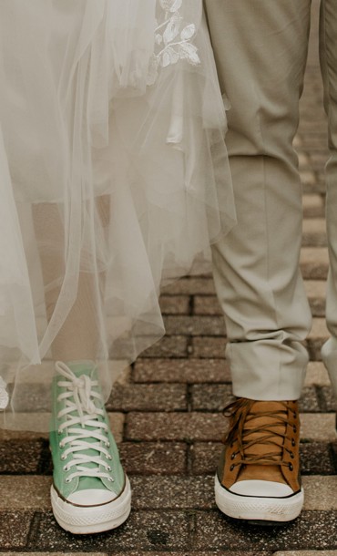 Couple in wedding outfits with trainers.