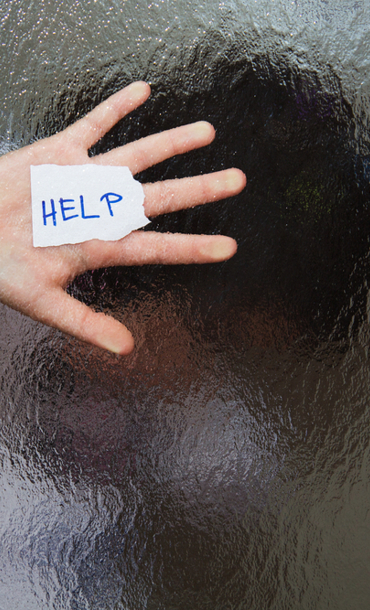 Hand holding paper, with the word 'help' written on it, up to glass