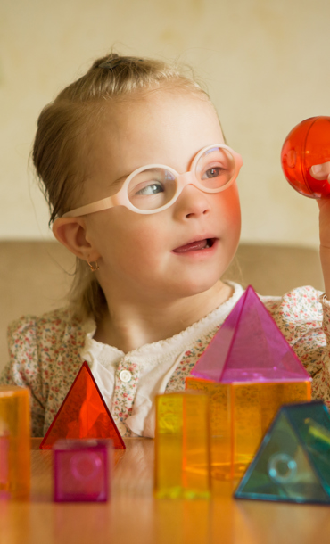 Child with disability playing with coloured and shaped blocks.