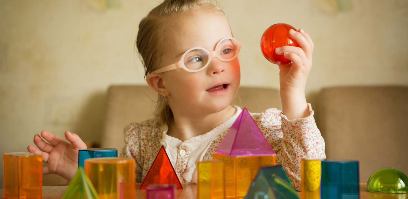 nojs Child with disability playing with coloured and shaped blocks.