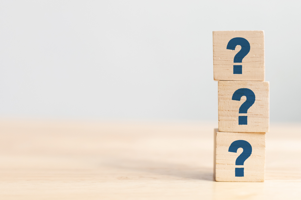 Wooden cube block shape with sign question mark symbol on wood table.
