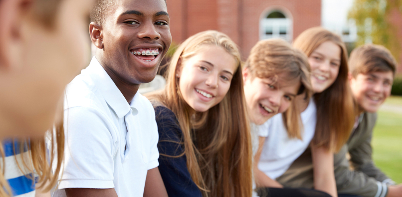 nojs Group of teenage students sitting outside school