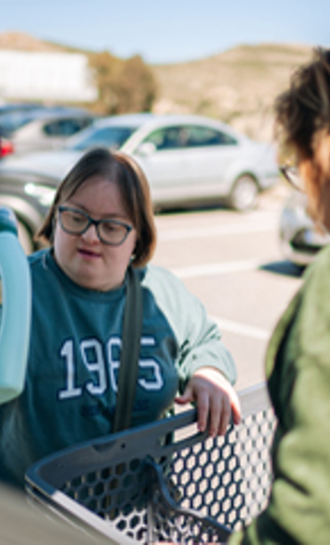 Woman and young person putting shopping in a car