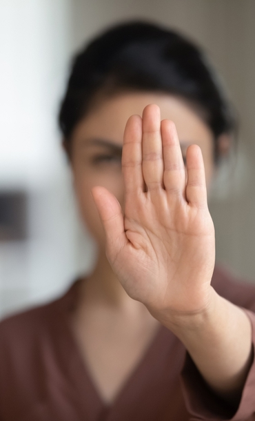 Woman holding her hand in front of her face to indicate stop or no.