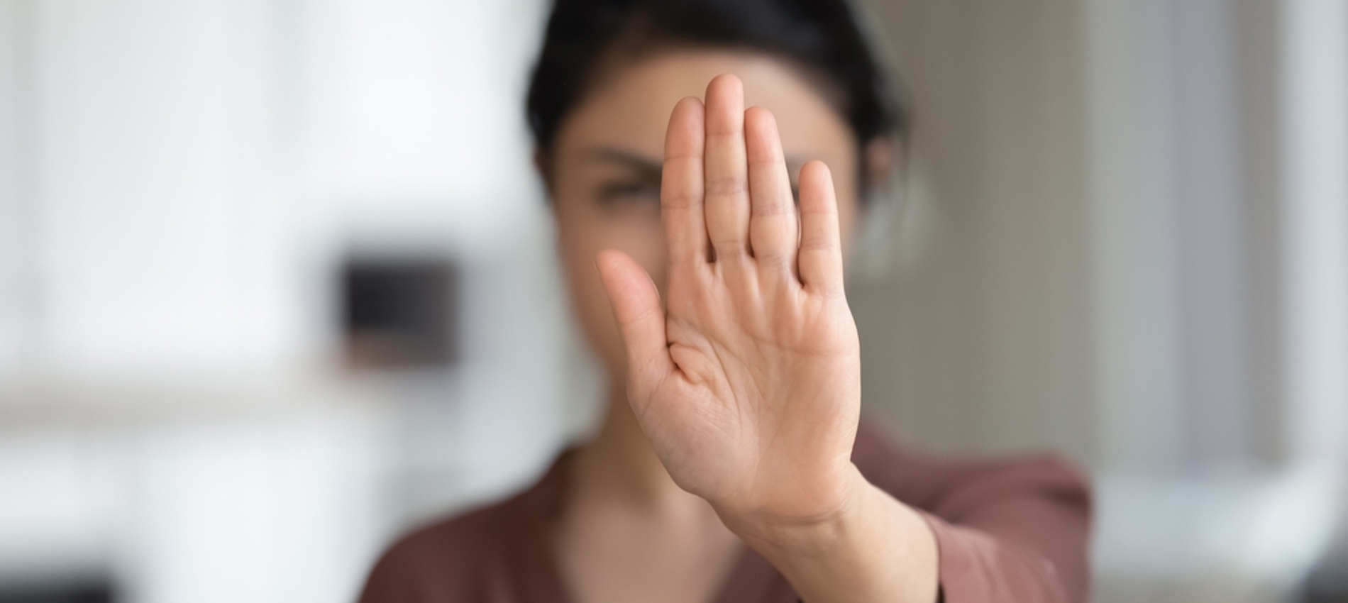 nojs Woman holding her hand in front of her face to indicate stop or no.