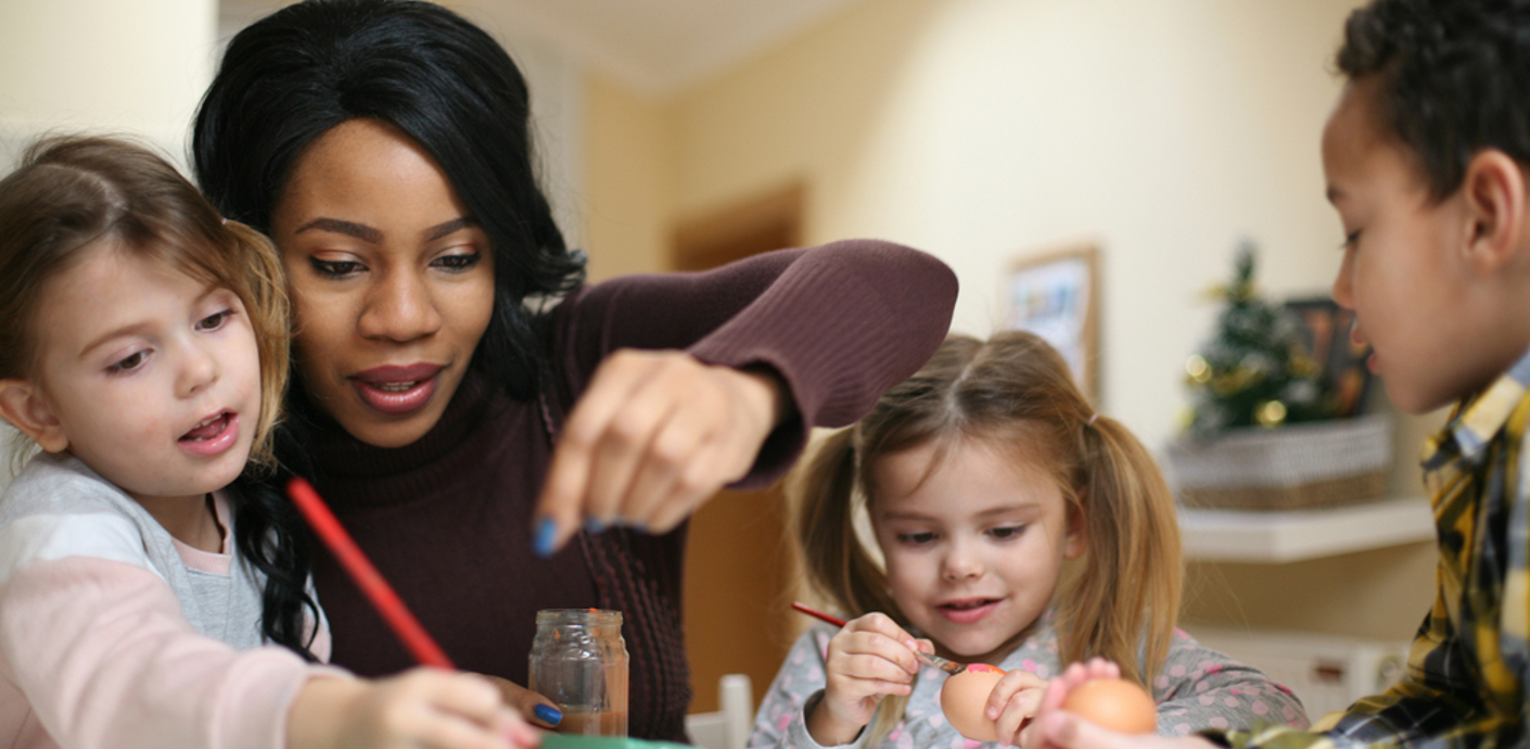 Adult with 3 children playing round a table
