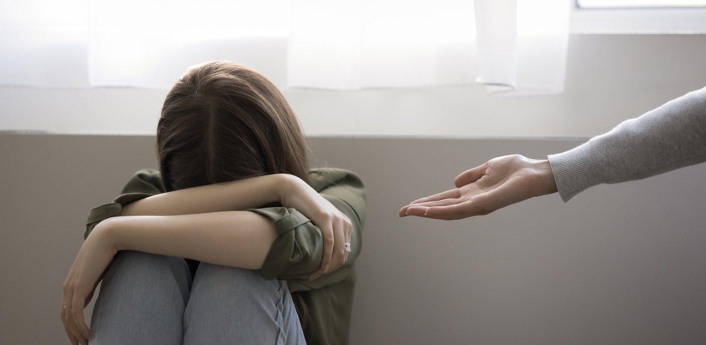 nojs Woman sitting on floor covering head with hands and with another person's outstretched arm offering help