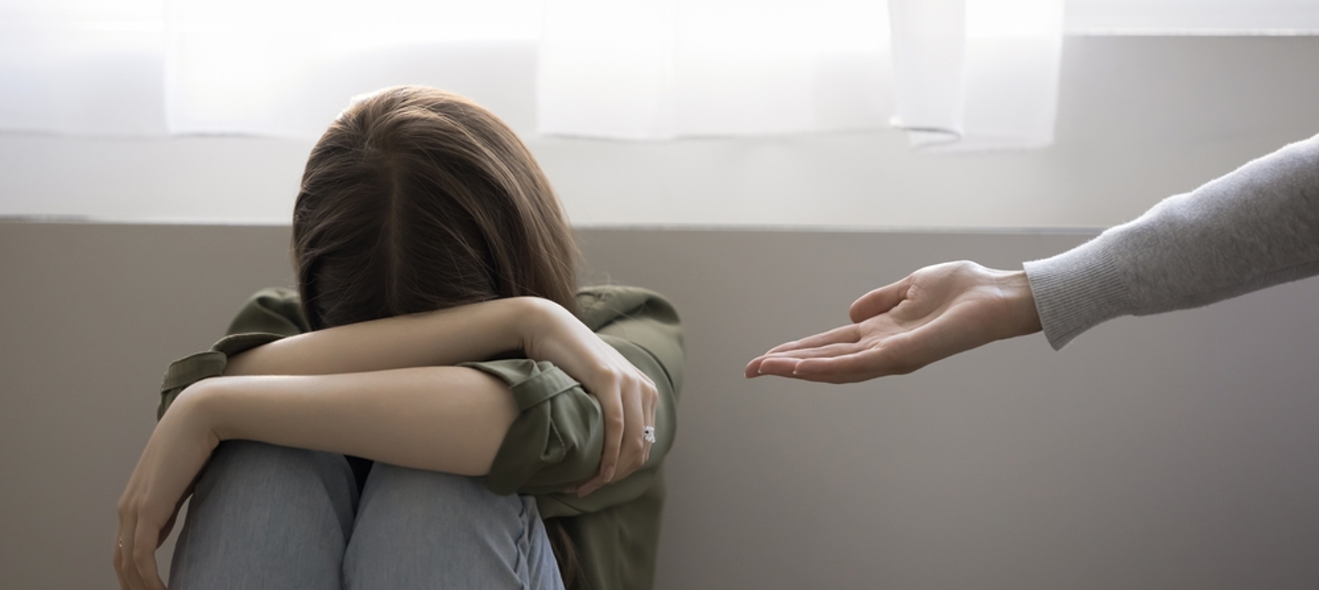 nojs Woman sitting on floor covering head with hands and with another person's outstretched arm offering help